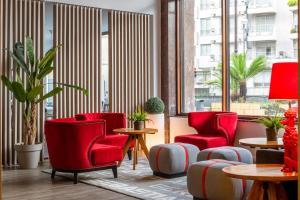 a lobby with red chairs and tables and windows at Hotel San Sebastián Orly, Affiliated by Meliá in Donostia-San Sebastián