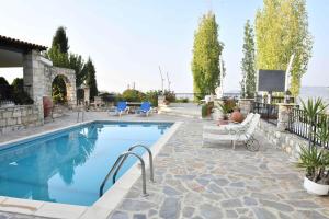 a swimming pool with a patio with chairs and a tv at Lasa Black Rock villa in Paphos
