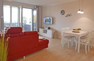 a living room with a red couch and a table at Baabe Villen Ensemble FeWo 13 Stra in Baabe