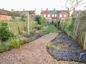 un jardin avec une clôture et un chemin en gravier dans l'établissement Carrstone Cottage, à Heacham