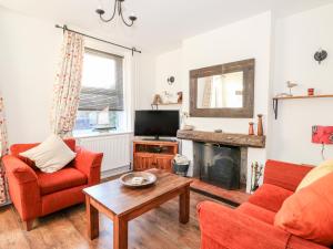 un salon avec des chaises rouges et une cheminée dans l'établissement Carrstone Cottage, à Heacham