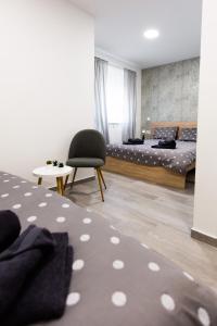 a bedroom with a bed and a chair at Gloria Rooms in Požega