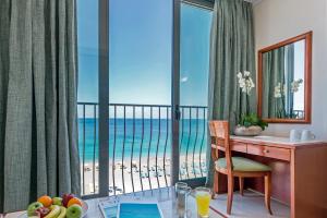 a room with a desk and a view of the beach at Mitsis La Vita in Rhodes Town