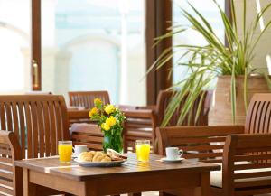 a wooden table with a plate of food and glasses of orange juice at Mitsis La Vita in Rhodes Town