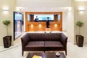 a woman walking in a lobby with a couch at Mitsis La Vita in Rhodes Town