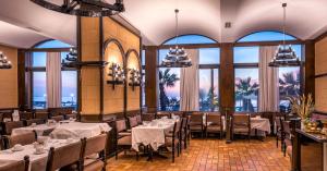 - une salle à manger avec des tables, des chaises et des fenêtres dans l'établissement Mitsis La Vita, à Rhodes