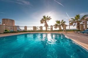 a large swimming pool with palm trees in the background at Mitsis La Vita in Rhodes Town