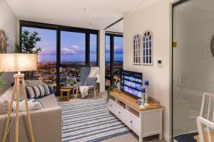 ein Wohnzimmer mit einem TV und ein Wohnzimmer mit Fenstern in der Unterkunft Hamptons Retreat on Level 77 Skytower in Brisbane