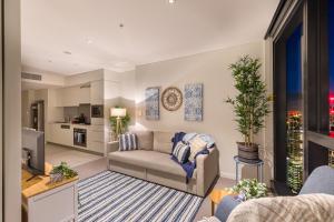 a living room with a couch and a tv at Hamptons Retreat on Level 77 Skytower in Brisbane