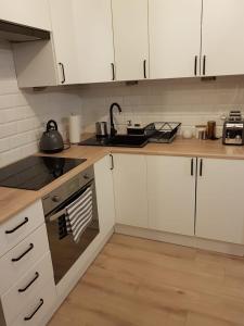 uma cozinha com armários brancos e um forno com placa de fogão em Apartament Monika em Klodzko