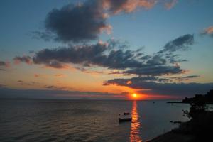 una puesta de sol sobre el océano con barcos en el agua en Blue Sky Apartments & Rooms, en Xiropigado