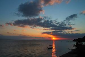 a sunset over the ocean with boats in the water at Blue Sky Apartments & Rooms in Xiropigado