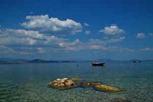 a boat in the water with rocks in the water at Blue Sky Apartments & Rooms in Xiropigado