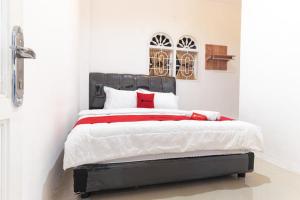 um quarto com uma cama com um cobertor vermelho e branco em Reddoorz @ Medan Johor em Medan