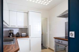 a kitchen with white cabinets and a sink at Appartement rue de Rennes - Gaîté in Paris