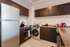 a kitchen with a refrigerator and a washing machine at Quintessential Quarters - Breathtaking 29th Floor Views in Dubai