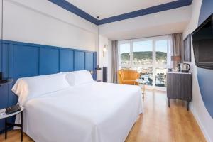 a bedroom with a white bed and a large window at Hotel San Sebastián Orly, Affiliated by Meliá in Donostia-San Sebastián