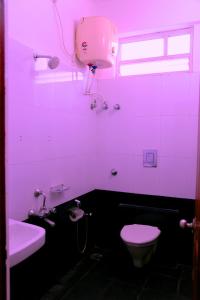 Baño de color rosa con aseo y lavamanos en Airport Gateway Hotel, en Devanhalli