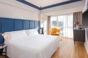 a bedroom with a large white bed and a blue wall at Hotel San Sebastián Orly, Affiliated by Meliá in Donostia-San Sebastián
