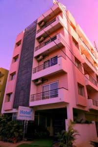 um edifício rosa com uma placa de hotel em frente em Airport Gateway Hotel em Devanhalli