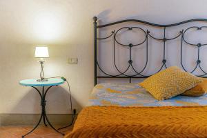 a bed with an orange blanket and a lamp on a table at Agriturismo La Colmata in Cesa