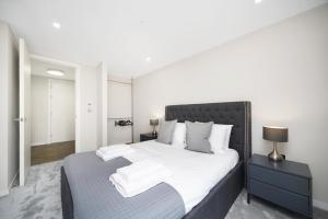 una camera da letto con un grande letto con lenzuola e cuscini bianchi di Lux Apartments in Fulham a Londra