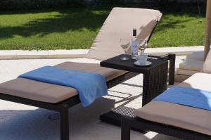 a wicker chair and a table with two glasses of wine at Vello Apartments in Byala
