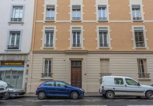 dos autos estacionados en un estacionamiento frente a un edificio en Le Cocon Lita-Palace, en Lyon