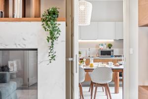 cocina con armarios blancos, mesa y sillas en Darsena Apartments by Wonderful Italy, en Siracusa