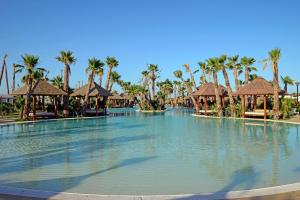 a large swimming pool at a resort with palm trees at Alannia Costa Blanca in Crevillente