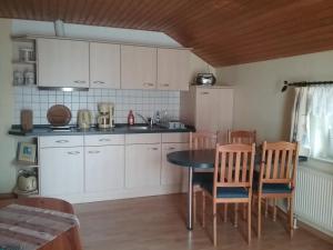a kitchen with white cabinets and a table and chairs at Seeidyll in Zemitz