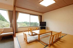a room with a table and chairs and a television at Kagetsuen in Hakone