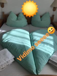 Una cama con dos almohadas verdes con un sol. en vidimo se en Selzthal