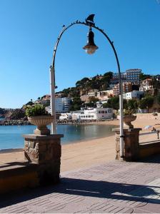 a street light with a bird on it next to a beach at Nuevo Luminoso Apartamento Catalina a 80 metros de la playa para 4 personas in Sant Feliu de Guixols