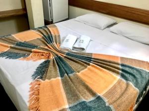 a bed with a blanket on it with two remote controls at Pousada Ouro de Minas in Diamantina