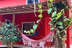 uma rede em frente a uma casa vermelha com plantas em Trancoso, Bahia - Casa por temporada com estacionamento em Trancoso
