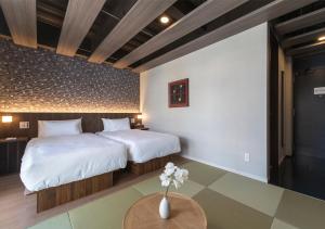 Un dormitorio con 2 camas y una mesa con flores. en 谷町君・ホテルひとめぼれ 京都四条烏丸, en Kioto