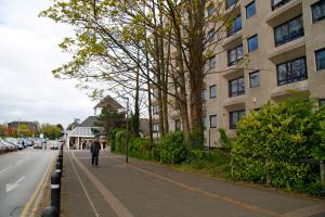 a man walking down a street next to a building at Portfolio Apartments - Stevenage Town Centre in Stevenage