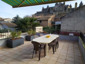 uma mesa e cadeiras numa varanda com um castelo em L'Atelier de Robert em Carcassonne