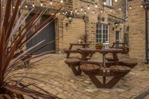 patio ze stołami piknikowymi i oświetleniem strunowym w obiekcie Norfolk Arms w mieście Glossop