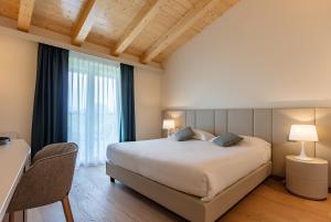 1 dormitorio con cama grande y ventana grande en Leonardo Hotel Lago di Garda - Wellness and Spa, en Lazise