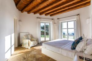 a bedroom with a bed and a chair and windows at Zen Residence in Lia beach in Kalafatis +41 photos