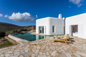 a white house with a swimming pool and two lounge chairs at Zen Residence in Lia beach in Kalafatis