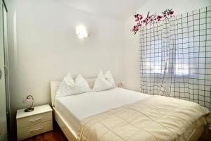 a bedroom with a bed with white sheets and a window at Apartments Villa Plaza in Trogir