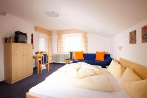 1 dormitorio con 1 cama blanca y 1 sofá azul en Franzele Appartements & Breakfast, en Sölden