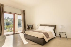 a bedroom with a bed and a large window at Villa Landolina in Noto