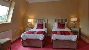 
a hotel room with two beds and two lamps at The Moorings Hotel & Seafood Restaurant in Portmagee
