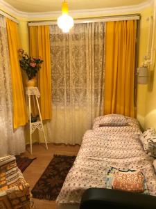 a bedroom with a bed and a window with yellow curtains at Kereki Retro Vendégház in Kerekegyháza