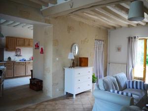 a living room with a blue couch and a kitchen at Gite Les Volets Rouges in Vigny