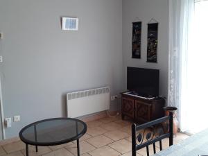 sala de estar con mesa de cristal y TV en Gite au coeur de Provence en LʼIsle-sur-la-Sorgue